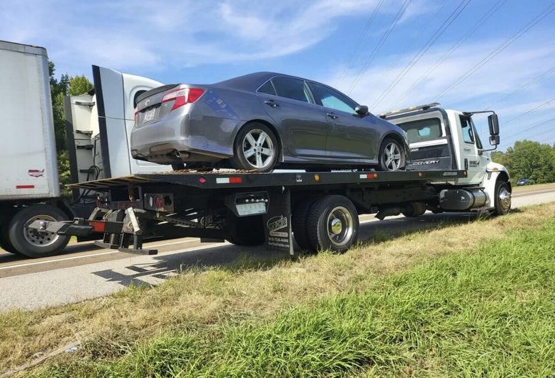 Long-distance towing service transporting a vehicle on the highway near Brookline, MA